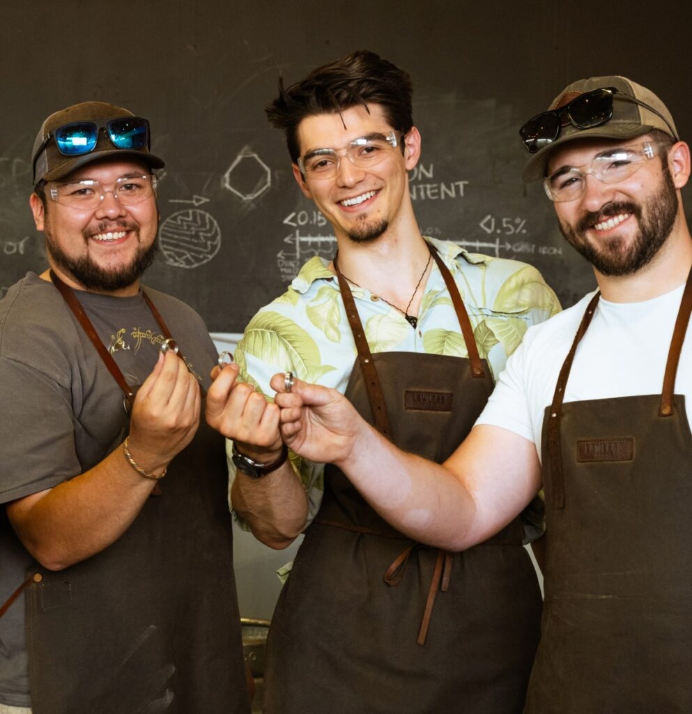 Students smiling and showing forged metal pieces made during a hands-on blacksmithing workshop.